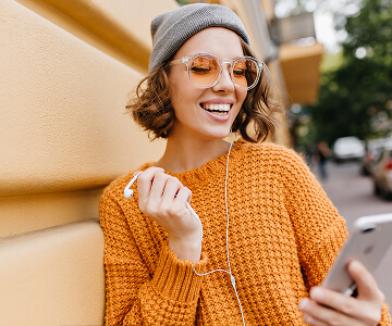 Smiling woman in glasses checking phone outdoors